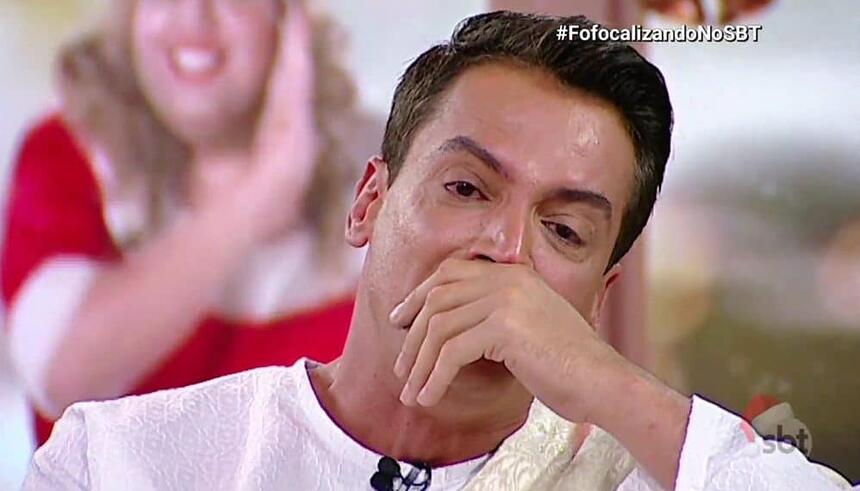 Leo Dias de camisa manga longa branca, com a mão na boca, chorando durante o Fofocalizando, do SBT