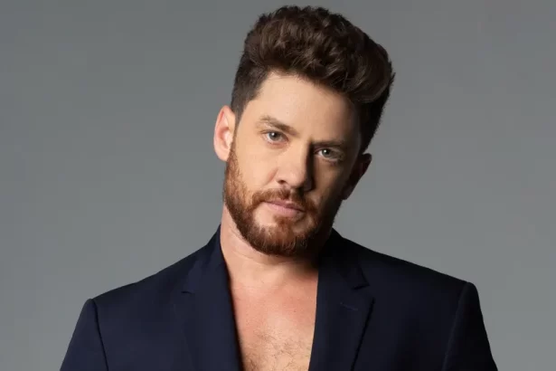 Leonardo Miggiorin de blazer azul, de barba, semblante sério durante sessão de fotos no estúdio