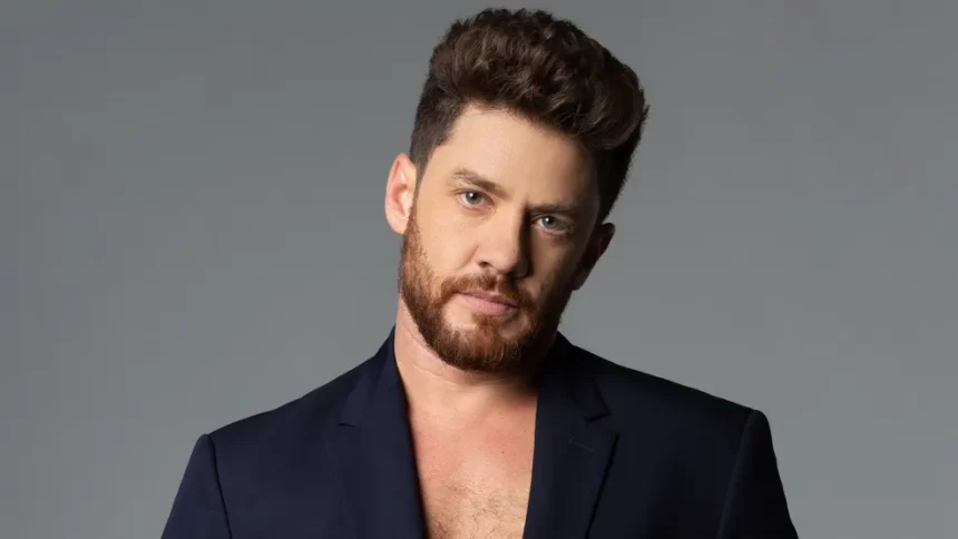 Leonardo Miggiorin de blazer azul, de barba, semblante sério durante sessão de fotos no estúdio