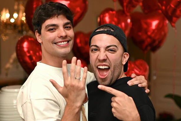 Lucas Rangel e Lucas Bley mostrando as alianças num quarto de hotel em São Paulo