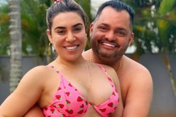 Naiara Azedo de biquine rosa, sorrindo, com argola grande, abraçada com Raphael