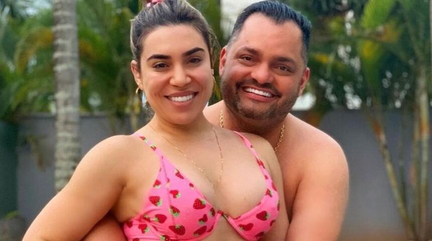 Naiara Azedo de biquine rosa, sorrindo, com argola grande, abraçada com Raphael