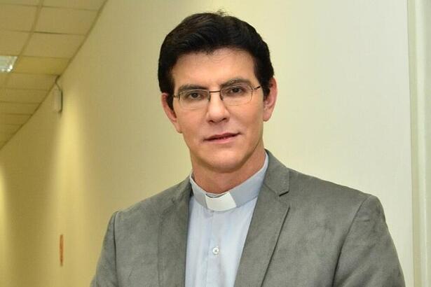 Padre Reginaldo Manzotti de blazer cinza, camisa social branca por dentro, de óculos, sorrindo