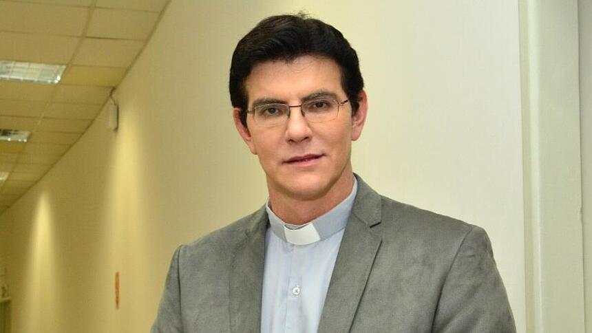 Padre Reginaldo Manzotti de blazer cinza, camisa social branca por dentro, de óculos, sorrindo