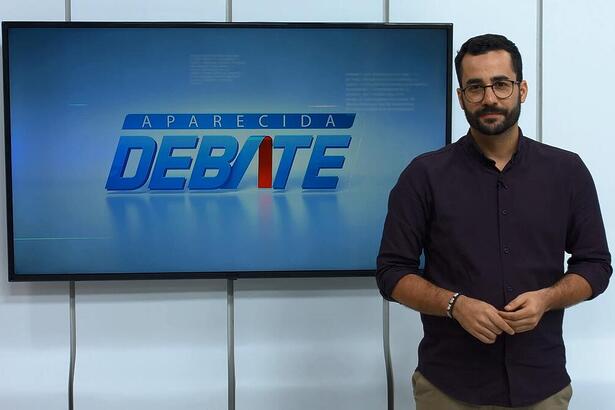 Guilherme Machado apresentando o Aparecida Debate na frente do telão