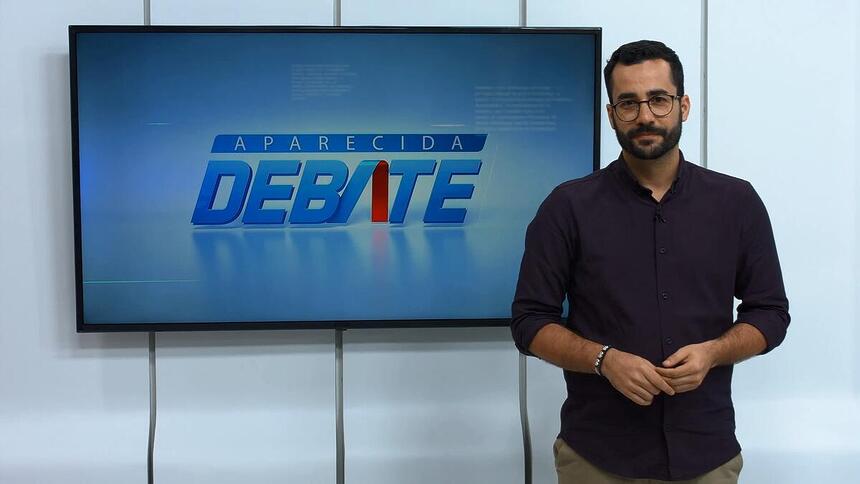 Guilherme Machado apresentando o Aparecida Debate na frente do telão