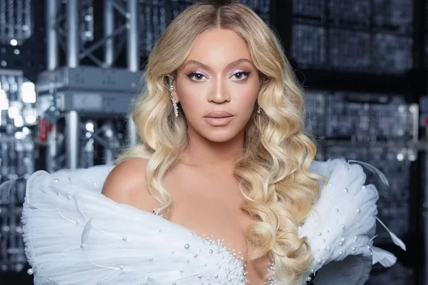 Beyoncé de lace loira, com semblante sério, de vestido branco durante show nos Estados Unidos