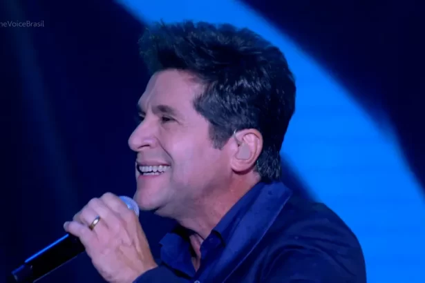 Daniel de blazer azul, de perfil, segurando microfone durante performance no The Voice Brasil