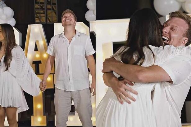 Gabi Luthai e Teo Teló de look branco, de mãos dadas, sorrindo, olhando pra cima durante Chá de Revelação