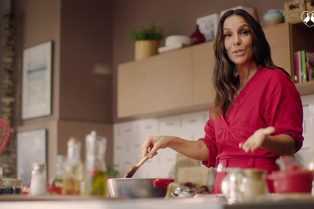 Ivete Sangalo de vestido vermelho cozinhando durante gravação do comercial da Perdigão