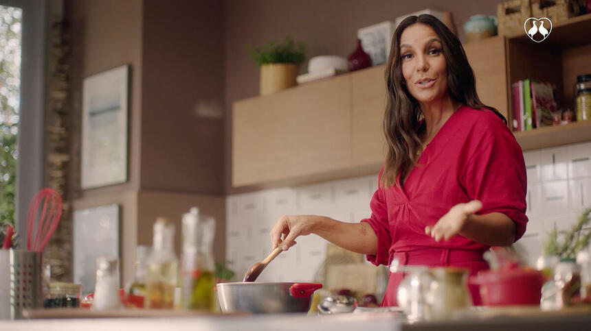 Ivete Sangalo de vestido vermelho cozinhando durante gravação do comercial da Perdigão