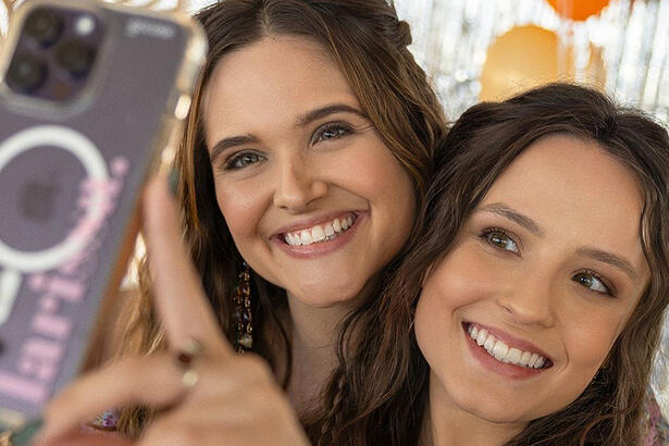 Juliana Paiva e Larissa Manoela sorrindo, fazendo selfie, durante gravação de série da Netflix