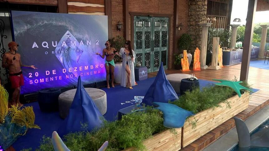 WL, Lily Nobre e Jaquelline apontam para o telão com o banner do Aquaman 2 na beira da piscina de A Fazenda 15