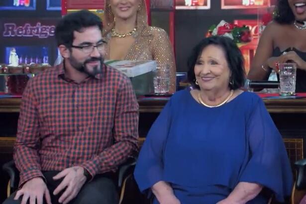 Padre Fábio de Melo olha para Dona Dea que está sorrindo sentada no Domingão