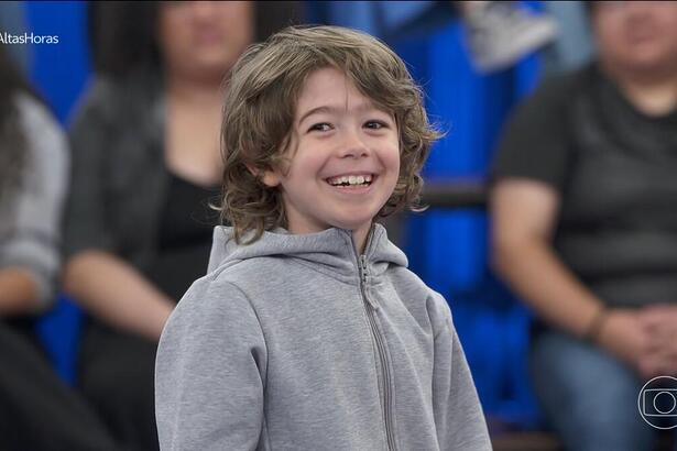 Thomas, filho de Serginho Groisman, sorrindo no centro do palco do Altas Horas