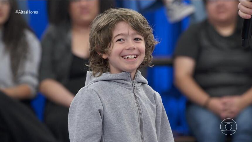 Thomas, filho de Serginho Groisman, sorrindo no centro do palco do Altas Horas