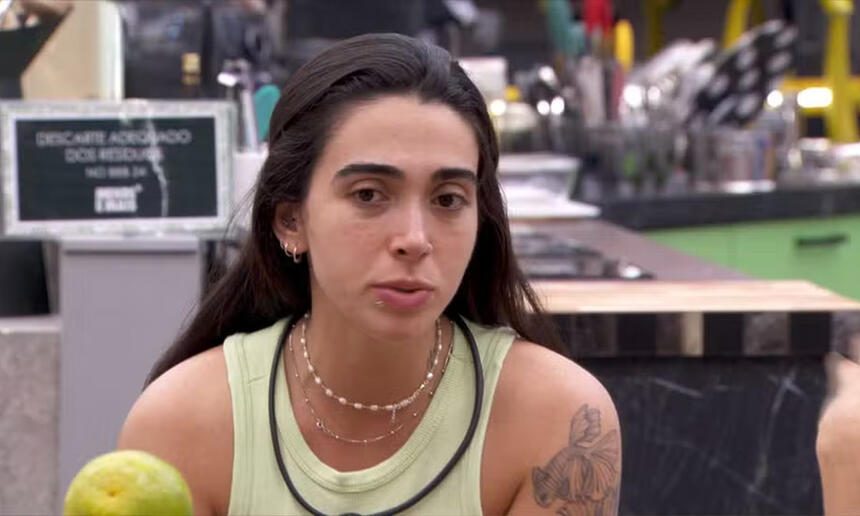 Giovanna de regata, microfone, cabelo preso, sentada na cozinha do BBB 24