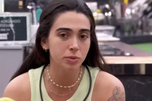 Giovanna de regata verde, cabelo preso, sentada na cozinha do BBB 24