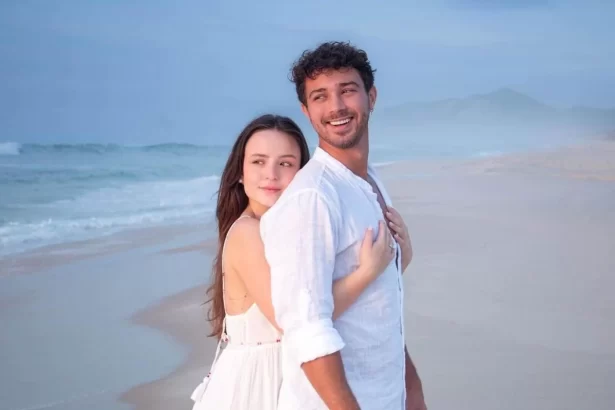 Larissa Manoela e André Luiz de branco, abraçados durante ensaio fotográfico na praia