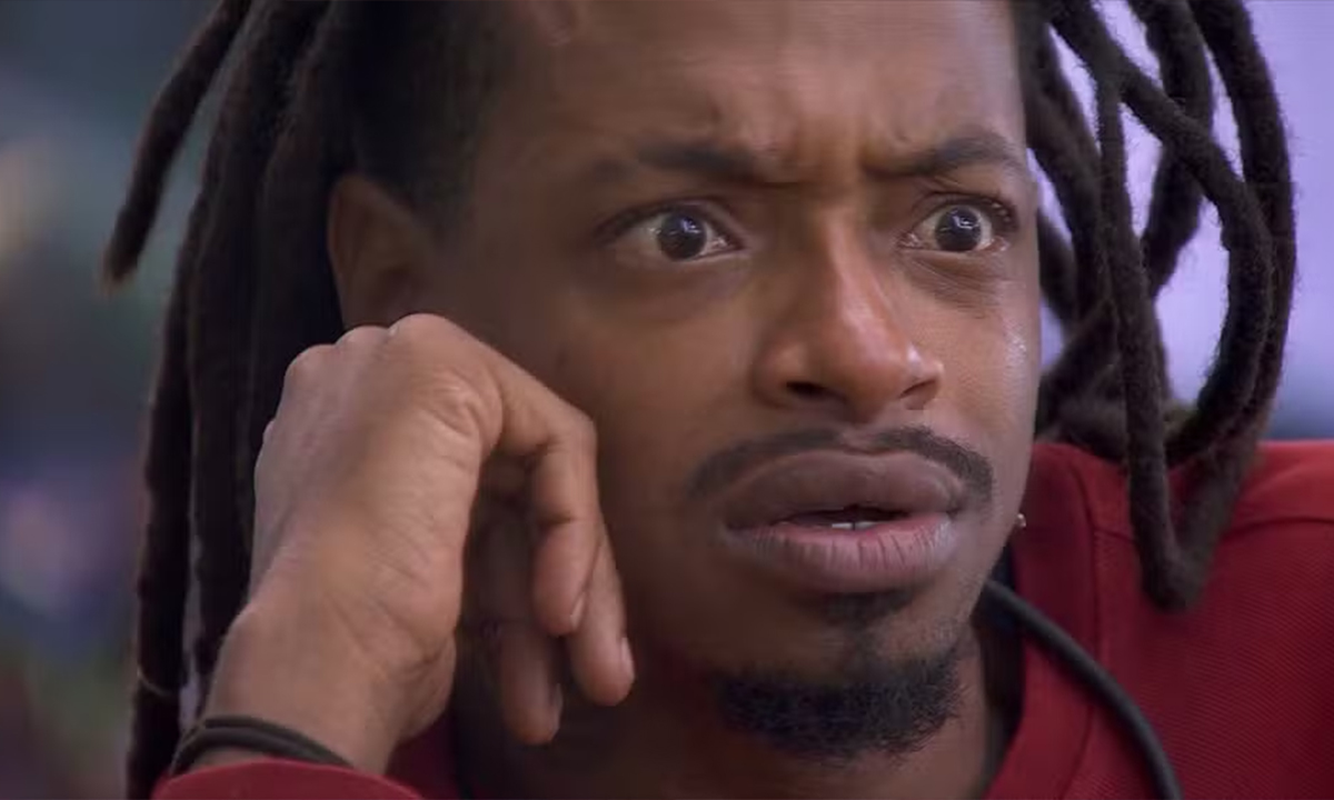 Lucas Luigi de camisa vermelha, sentado, com a mão no rosto durante conversa na varanda do BBB 24