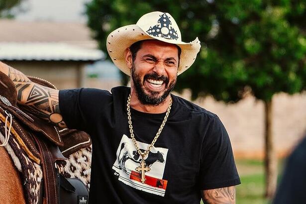 João Carreiro sorrindo ao lado de um cavalo. Ele será homenageado no Aparecida Sertaneja