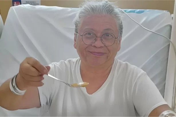 Marlene Mattos sorrindo, segurando uma colher de papa, sentada numa maca