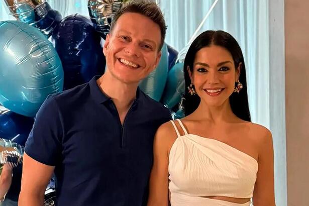 Michel Teló e Thais Fersoza em foto posada em frente uma decoração azul de aniversário