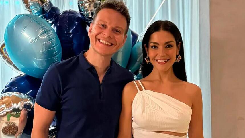 Michel Teló e Thais Fersoza em foto posada em frente uma decoração azul de aniversário