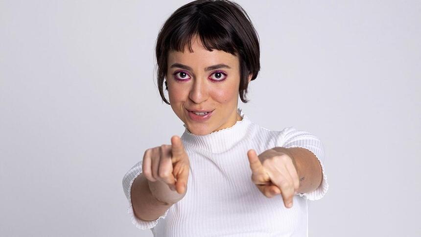 Valentina Bandeira de camisa branca, apontando pra câmera, cabelo curto, preto, durante ensaio fotográfico