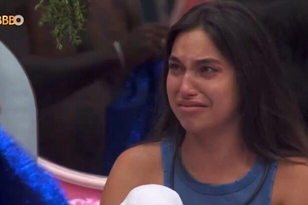 Vanessa Lopes de camisa regata azul, chorando, sentada na cama do BBB 24