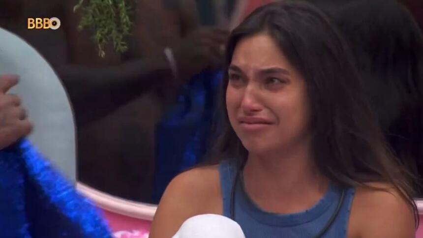 Vanessa Lopes de camisa regata azul, chorando, sentada na cama do BBB 24