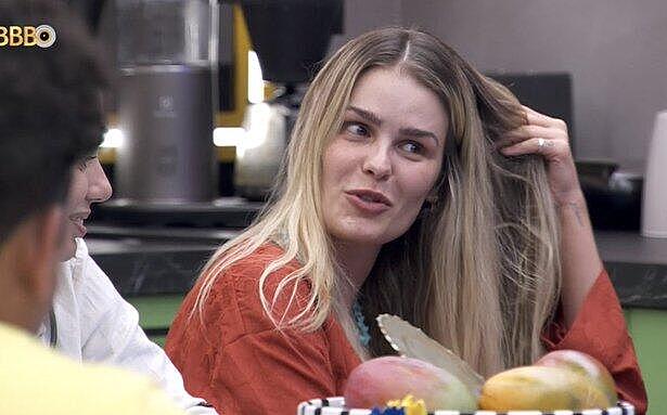 Yasmin Brunet sentada, de camisa marrom, mexendo no cabelo no BBB 24