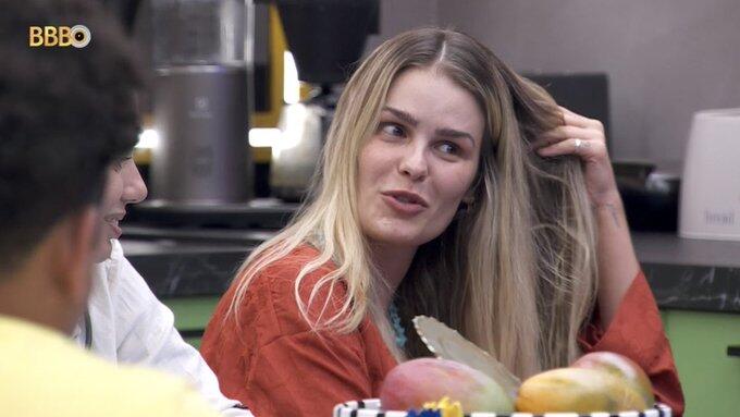 Yasmin Brunet sentada, de camisa marrom, mexendo no cabelo no BBB 24