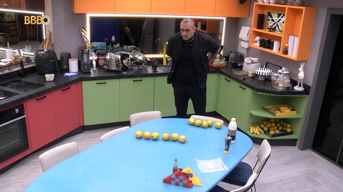 Mc Bin Laden olhando para a mesa na cozinha do BBB 24