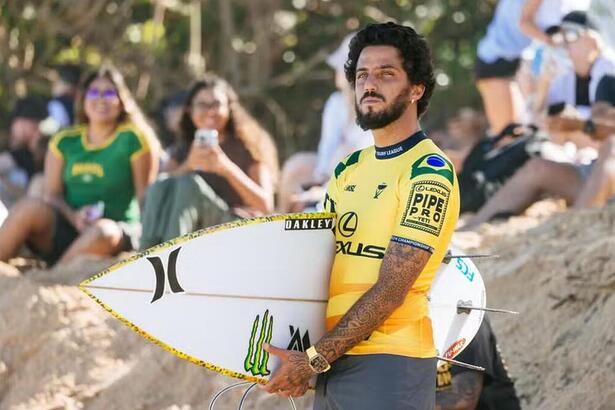 Filipe Toledo com uma prancha de surfe em baixo do braço