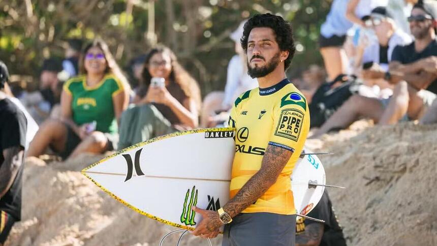 Filipe Toledo com uma prancha de surfe em baixo do braço