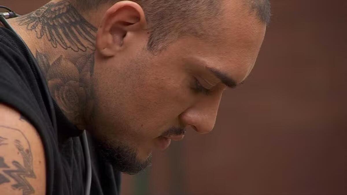MC Bin Laden de cabeça baixa e sentado na sala do BBB 24