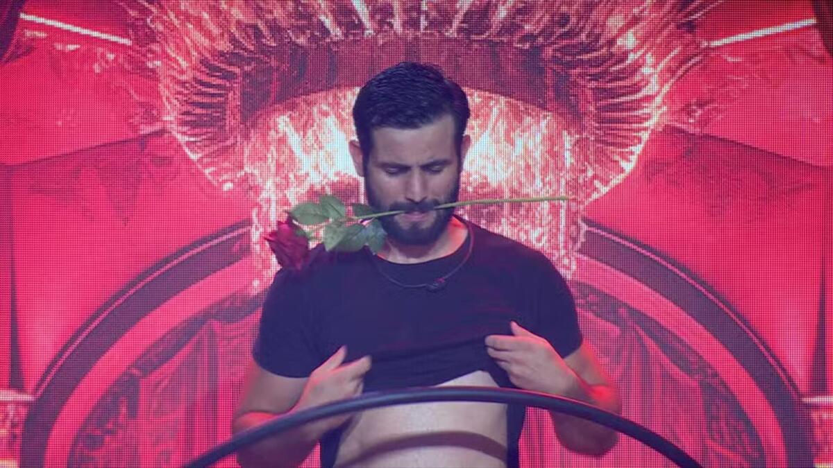 Matteus com uma rosa na boca e sensualizando na festa do BBB