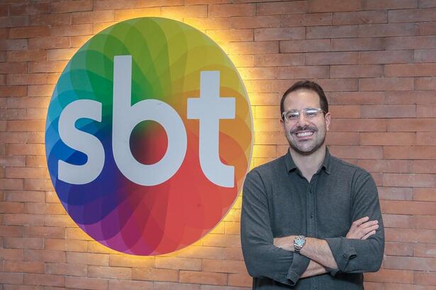 Paulo Mathias na frente do logotipo do SBT