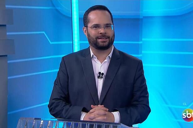 Marcelo Casagrande sorrindo no cenário do SBT News na TV