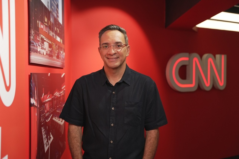 Maurício Noriega na frente do  logo da CNN Brasil