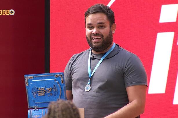 Michel sorrindo com o colar de anjo do BBB 24 no pescoço