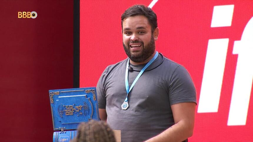 Michel sorrindo com o colar de anjo do BBB 24 no pescoço