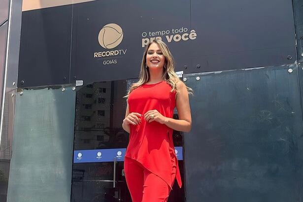 Nahyara Moura de conjunto vermelho em frente a sede da Record Goiás