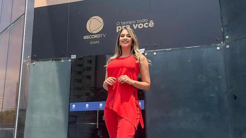 Nahyara Moura de conjunto vermelho em frente a sede da Record Goiás