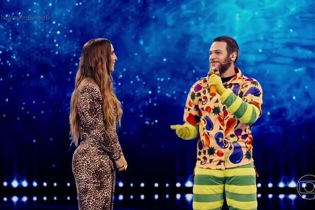 Ivete Sangalo e Emilio Dantas no palco do The Masked Singer Brasil. Emílio Dantas está com parte da fantasia de alface