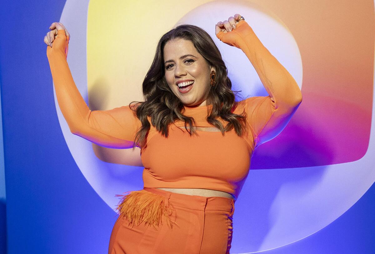 Tati Machado dançando à frente do logo da Globo