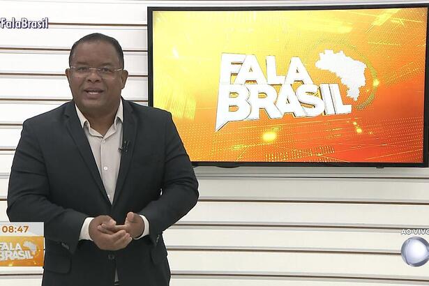 Evenilson Santana no cenário antigo da TV Guararapes, em frente a tela com o logo do Fala Brasil