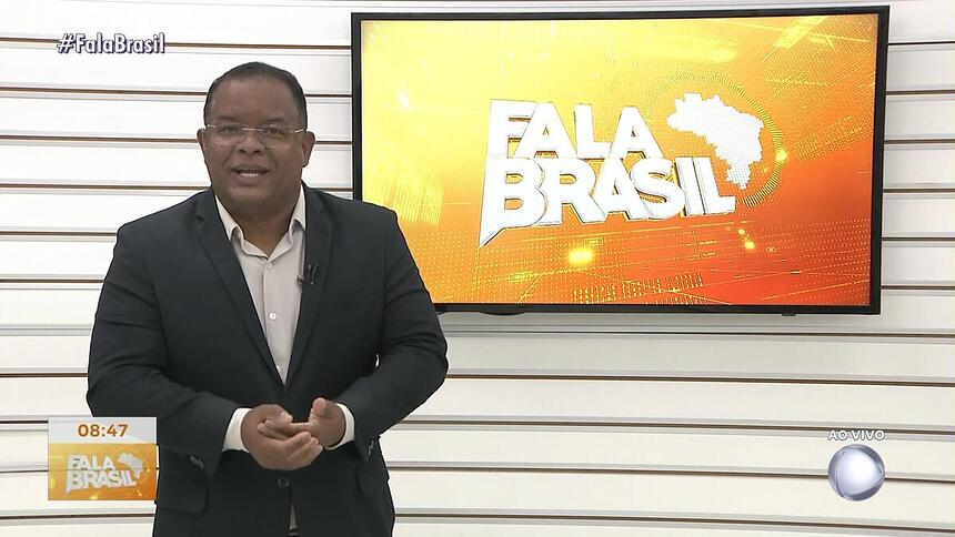 Evenilson Santana no cenário antigo da TV Guararapes, em frente a tela com o logo do Fala Brasil