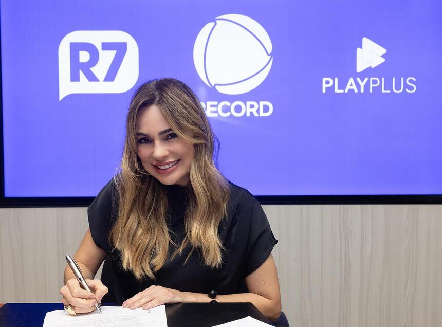 Rachel Sheherazade usa blusa preta e está sorrindo ao assinar contrato com a Record